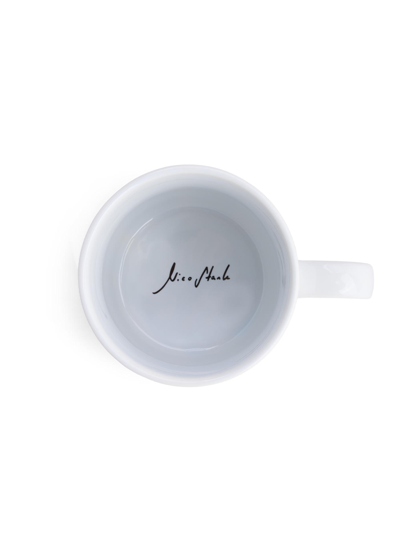 Blick von oben auf eine weiße Tasse mit schwarzer Signatur „Nico Stank“ auf dem Tassenboden.